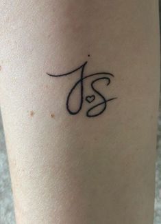 a woman's leg with a tattoo on it that has the letter j in cursive writing