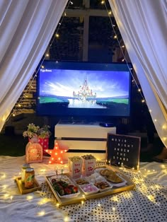 a table topped with trays filled with food next to a flat screen tv