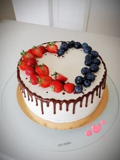 a white cake with chocolate icing and strawberries on top, sitting on a plate