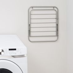 a white washer sitting next to a dryer in a room with a towel rack on the wall