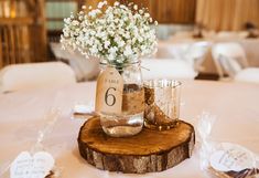 the table is set up for a wedding reception with flowers in mason jars and place cards