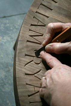 a person is carving the letters on a wooden table