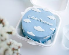 a blue cake with white clouds and the words c aver rostenma on it