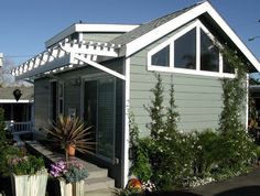 a gray house with white trim on the roof and windows, along with potted plants