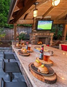 an outdoor bar is set up with food and drinks on the counter, along with two televisions