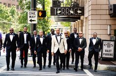 a group of men in tuxedos walking down the street