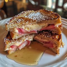 a grilled cheese and ham sandwich on a white plate with syrup drizzled around it