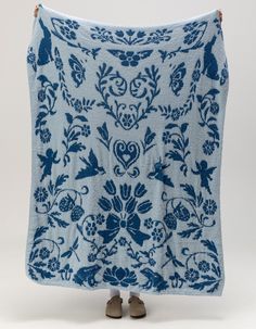 a blue and white blanket with floral designs on it, in front of a white background