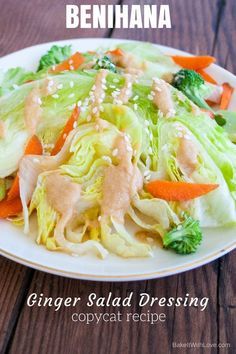 a white plate topped with lettuce and carrots covered in dressing next to broccoli