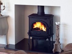 a living room with a fire place in the center and two brown chairs around it