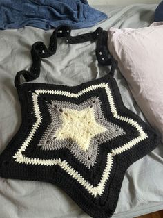 a crocheted bag sitting on top of a bed next to pillows and blankets