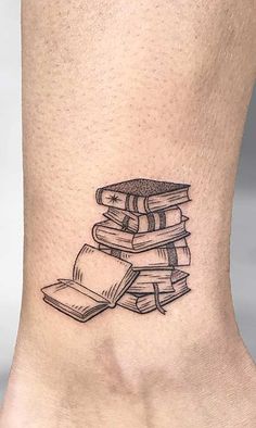 a black and white photo of a book tattoo on the ankle