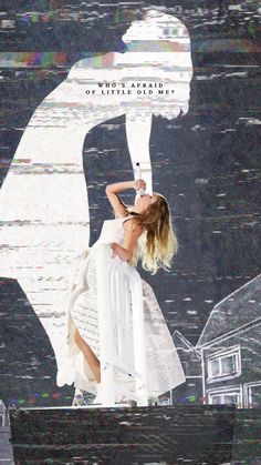 a woman standing on top of a white chair in front of a wall with an image of a man