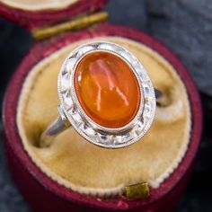 This gorgeous vintage ring features an oval cabochon cut Mexican fire opal That is accented with a reflective undulating border and milgrain details.  It is crafted in platinum and is currently a size 5.75.  The opal has a tiny nick on one end that cannot be seen while worn. Mexican Fire Opal Ring, Mexican Fire Opal, Fire Opal Ring, Vintage Mexican, Opal Ring, Vintage Ring, Oval Cabochon, Opal Rings, Fire Opal