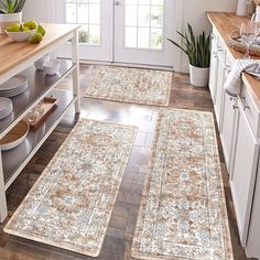 three rugs in the middle of a kitchen with fruit on the counter and plates