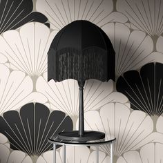 a lamp on a table in front of a wallpapered background with fan design