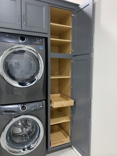 a washer and dryer in a room with gray cupboards on the wall