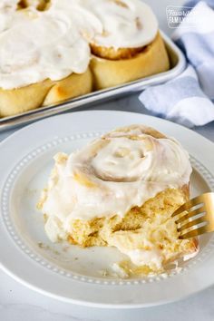 a white plate topped with frosted cinnamon rolls