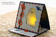 a halloween card with a ghost on it and an orange light in the shape of a boo