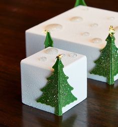 two small green christmas trees sitting on top of white blocks