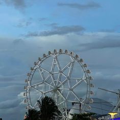 a ferris wheel sitting on top of a lush green field under a cloudy blue sky