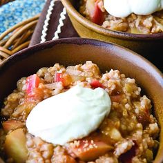 two brown bowls filled with oatmeal and fruit topped with whipped cream on top