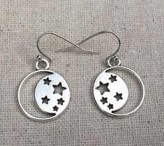 These are so cool and unique!  Silver discs with cutout stars and moon design.  They are eye catching and versatile.  The perfect everyday earrings for any star and moon lover.The earrings measure 5/8” long by 5/8” wide and hang from simple silver ear wire hooks.  Overall drop length is 3/4”.  Made from allergy free plated silver.I have a matching necklace in my shop, if you would like the whole set.  Here is the link......... https://etsy.me/2KOGpkx Thanks for stopping by!  Please take a moment Moon Phase Star Earrings For Gift, Nickel-free Star Shaped Symbolic Earrings, Symbolic Star-shaped Nickel-free Earrings, Symbolic Nickel-free Star Earrings, Bubble Earrings, Moon And Star Earrings, Silver Statement Earrings, Dragonfly Jewelry, Dragonfly Earrings