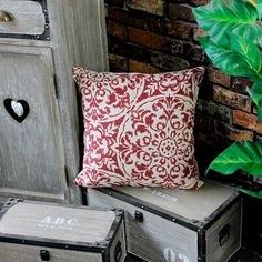 an old chest with two drawers and a pillow on it next to a potted plant