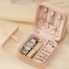 an open pink jewelry box on top of a white bed with rings and bracelets in it