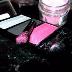 some pink and white glitters are in a jar next to a cell phone on a table