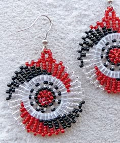 red, black and white beaded earrings on sand