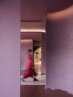 a woman in a red dress is walking through a purple room with a circular doorway