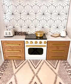 a white stove top oven sitting inside of a kitchen next to a wall with geometric designs on it