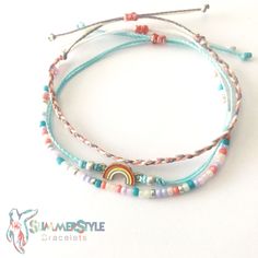 two bracelets with beads and a rainbow on the end are sitting next to each other