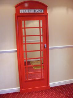 a red phone booth sitting next to a wall