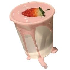 a strawberry in a milkshake with pink glaze on the rim and green leaf