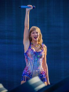 taylor swift performing on stage with her arms in the air while holding up a microphone