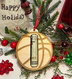 a basketball ornament hanging from a christmas tree with ornaments around it and a happy holiday sign in the background