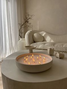 a lit candle is on top of a round table in front of a white couch