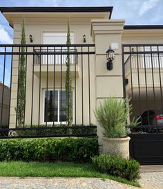 a house that has a fence in front of it and some plants on the side