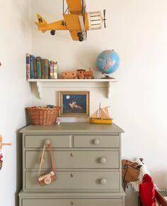 a toy airplane hanging from the ceiling above a dresser in a child's bedroom