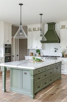 a large kitchen with an island in the middle and two pendant lights hanging from the ceiling