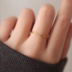 a woman's hand wearing a yellow gold ring with small white diamonds on it