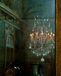 a chandelier hanging from the side of a wall in front of a mirror