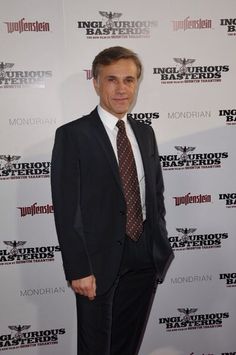 a man in a suit and tie standing on a red carpet