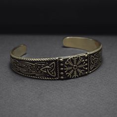 a gold bracelet with intricate designs on it