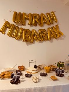 a table topped with lots of desserts and balloons that spell out the word urban