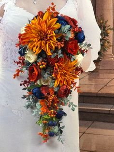 a bridal bouquet made up of orange and blue flowers on a mannequin