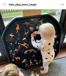 two children are playing with toys in front of a glass door that says kids play learn laugh