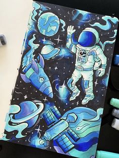 a drawing of an astronaut in space surrounded by blue and white markers, pencils and pens